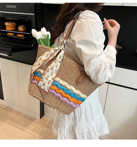 Dettaglio borsa tote in paglia intrecciata con strisce colorate e sciarpa floreale decorativa