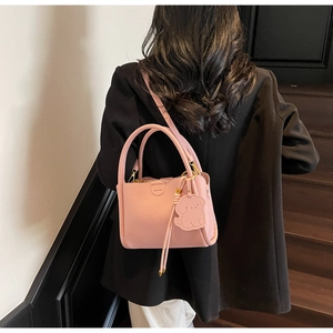 Detailed back view of pink lychee leather bucket bag with puppy charm and shoulder strap