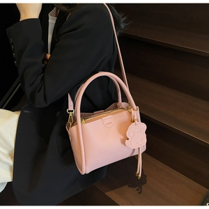 Detailed macro view of pink litchi grain leather bag with fashion tag and dog charm