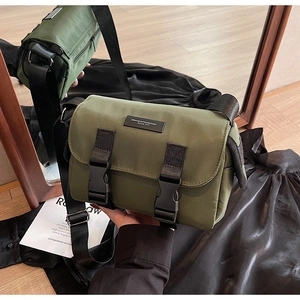 Detail of dark green nylon messenger bag with black plastic buckles and adjustable strap