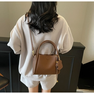 Detailed back view of brown lychee leather bucket bag with a cute bear charm accessory