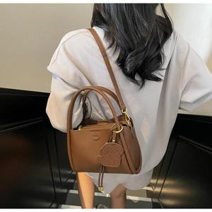 Detail of brown lychee grain leather bucket bag with top handle and puppy charm