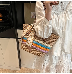 Dettaglio della borsa tote in paglia intrecciata con accenti colorati e sciarpa floreale