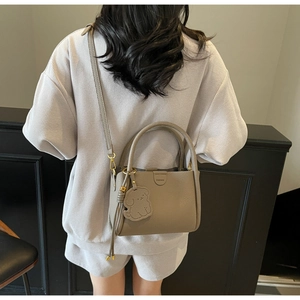 Detail of khaki leather bucket bag with dog charm and embossed fashion text