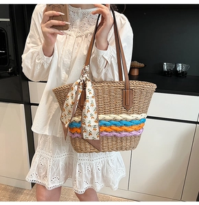 Dettaglio della borsa tote in paglia con strisce colorate e manici in pelle marrone