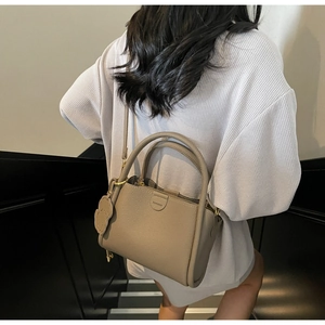 Close-up of lychee grain leather bucket bag with puppy charm and fashion metal detail