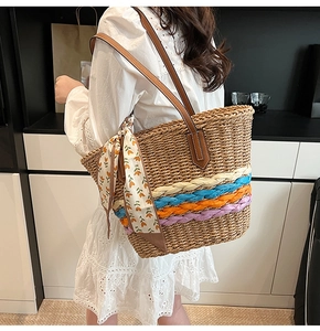 Dettaglio della borsa tote in paglia con strisce colorate e ciondolo a foulard a fiori