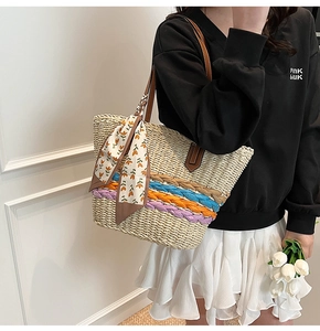 Dettaglio della borsa in paglia con strisce colorate intrecciate e foulard di seta a fiori