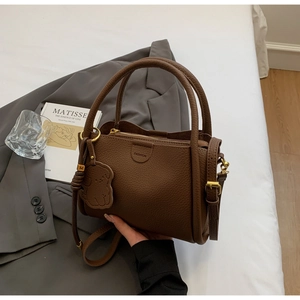 Detail of brown litchi leather handbag featuring gold hardware and fashion embossing