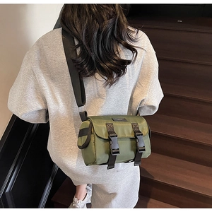 Detail of army green nylon messenger bag with double buckle closure on stairs