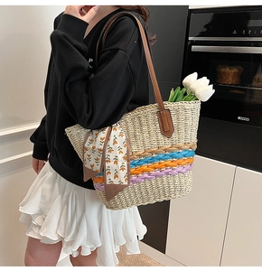 Dettaglio della borsa in paglia intrecciata con strisce colorate e foulard sul manico in pelle