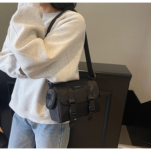 Detailed view of black nylon messenger bag with double plastic buckles and wide strap