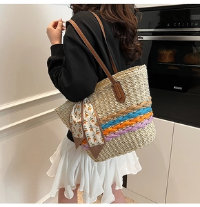 Dettaglio della borsa tote in paglia intrecciata con finiture colorate e foulard in seta