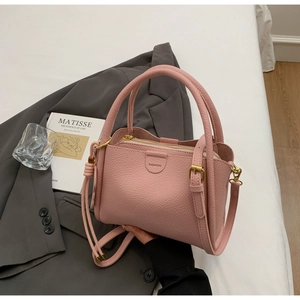 Close-up of pink lychee grain leather bucket bag with gold hardware and shoulder strap