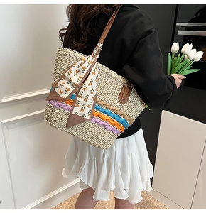 Dettaglio borsa shopper in paglia intrecciata con righe colorate e foulard a fiori
