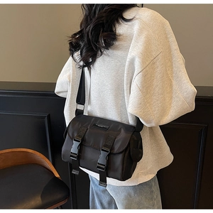 Close-up of black nylon messenger bag with double buckle straps and wide fabric shoulder strap