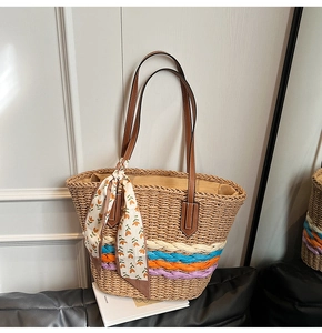 Dettaglio della borsa in paglia con strisce colorate e raffinato foulard in seta floreale
