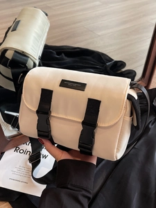Chic beige nylon messenger bag with black buckles and wide shoulder strap in mirror view