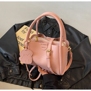 Detailed close-up of a pink litchi pattern bucket bag with a cute puppy charm and strap
