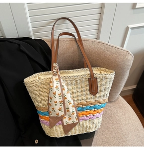 Dettaglio borsa tote in paglia con strisce colorate, manici in pelle e foulard floreale