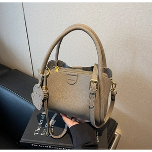 Detail view of grey lychee leather handbag with golden hardware and fashion logo