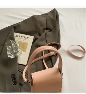 Detail of nude pink faux leather square handbag with top handle and metal buckle