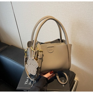 Detail of taupe pebbled leather bucket bag with dog charm on art books