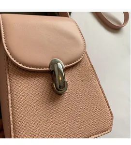 Detail of light pink crossbody bag with woven texture and silver metallic twist lock