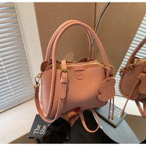 Detailed view of pink lychee leather handbag with cute dog charm and fashion label