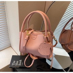 Detailed shot of pink pebble leather bucket bag with gold hardware and dog charm