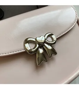 Detail of light pink leather saddle bag with silver bow hardware and heart center