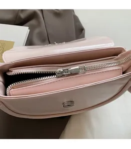 Detail of smooth silver zipper and interior lining of light pink saddle shoulder bag
