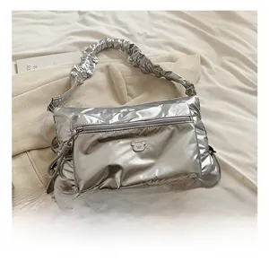 Detail view of metallic silver nylon crossbody bag with ruffled strap and bear logo