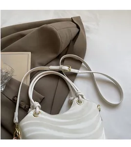 Detail of white wavy texture handbag with gold metal hardware and adjustable strap