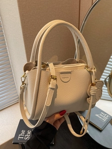 Chic beige lychee leather bucket bag with dual handles and gold hardware details