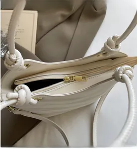 Detailed close-up of smooth gold zipper and knot handle on a pleated bucket bag
