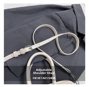 Detail view of adjustable shoulder strap and leather handle on cream small square bag
