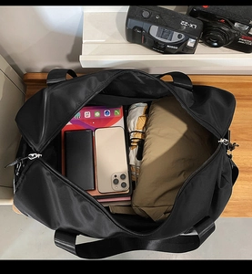 Vue de dessus d'un grand sac de sport noir contenant tablette, téléphone et vêtements
