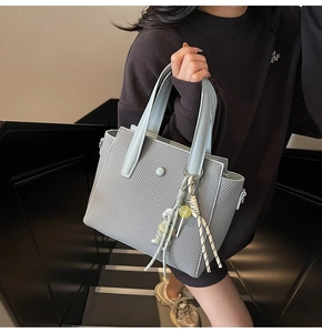 Détail du sac seau bleu clair avec texture gaufrée et breloque en perles décorative