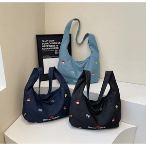 Dettaglio di borse tote in denim con ricami nei colori azzurro, blu scuro e nero fumo