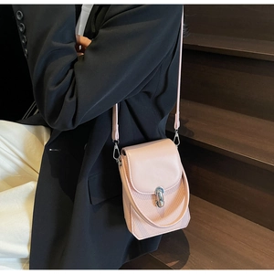 Close-up of light pink crossbody bag with silver lock worn by model on stairs