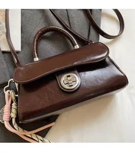 Détail du sac à main en cuir marron rétro avec fermoir argenté et charme tressé rose