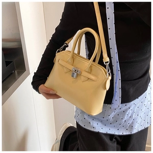 Detail of cream-colored small square handbag with silver buckle and leather strap