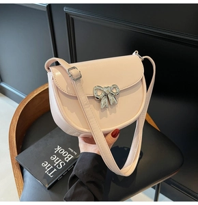 Detail showing the light pink saddle bag with a silver bow clasp on a black seat