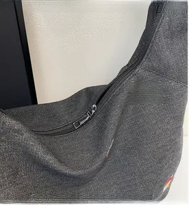 Dettaglio della cerniera in metallo e del tessuto denim nero della borsa tote