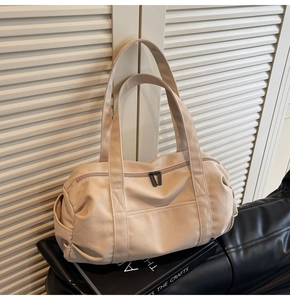 Close-up of beige canvas travel bag featuring durable wide handles and front pocket