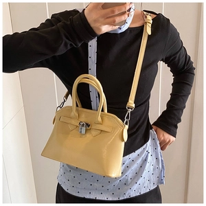 Detail of yellow glossy crossbody bag with metallic padlock and silver hardware