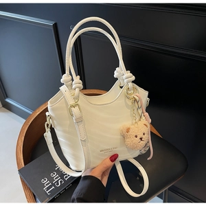 Close-up of a white bucket bag featuring wave texture and a cute brown bear charm