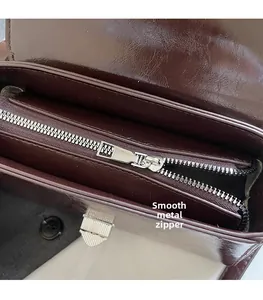 Détail de la fermeture éclair en argent et ferrures sur le sac en cuir bordeaux