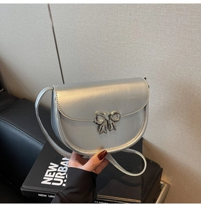 Detail of silver metallic saddle bag with large bow buckle and sleek faux leather finish